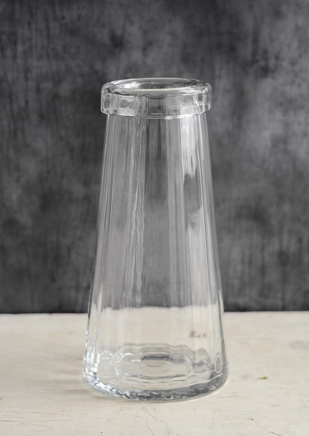 1: A tall, clear glass vase with slight fluted texture and rolled rim.