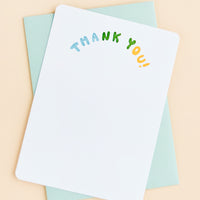 2: A white notecard with "Thank you" in colorblocked, arc-shaped text at top, paired with a turquoise envelope.