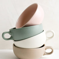 2: A stacked tower of pastel colored mugs with handles.