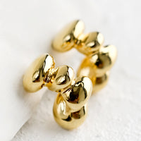 Gold: A pair of gold hoop earrings in melty blob shape.
