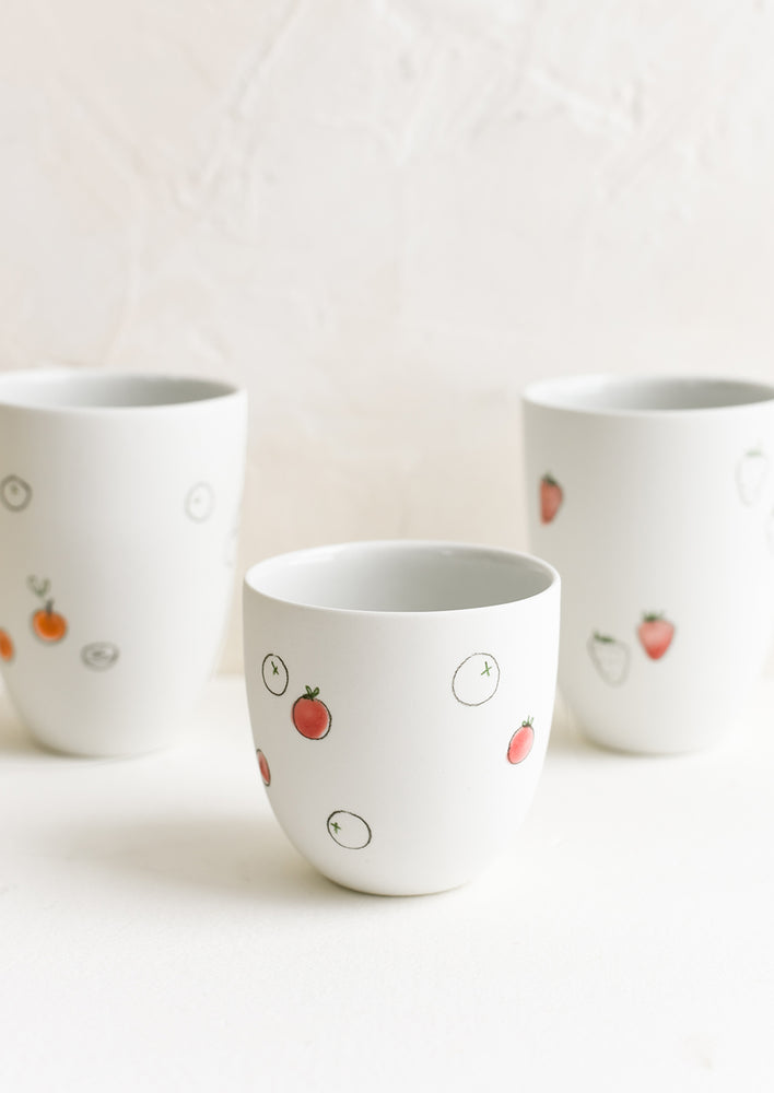 Small and large porcelain cups with hand drawn fruit sketches.