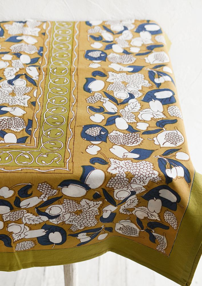 A tablecloth in ochre, navy and chartreuse floral and fruit print.