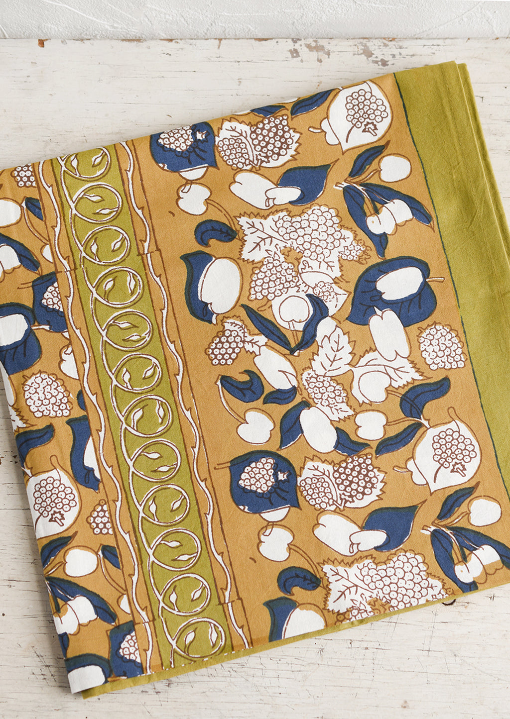 1: A tablecloth in ochre, navy and chartreuse floral and fruit print.