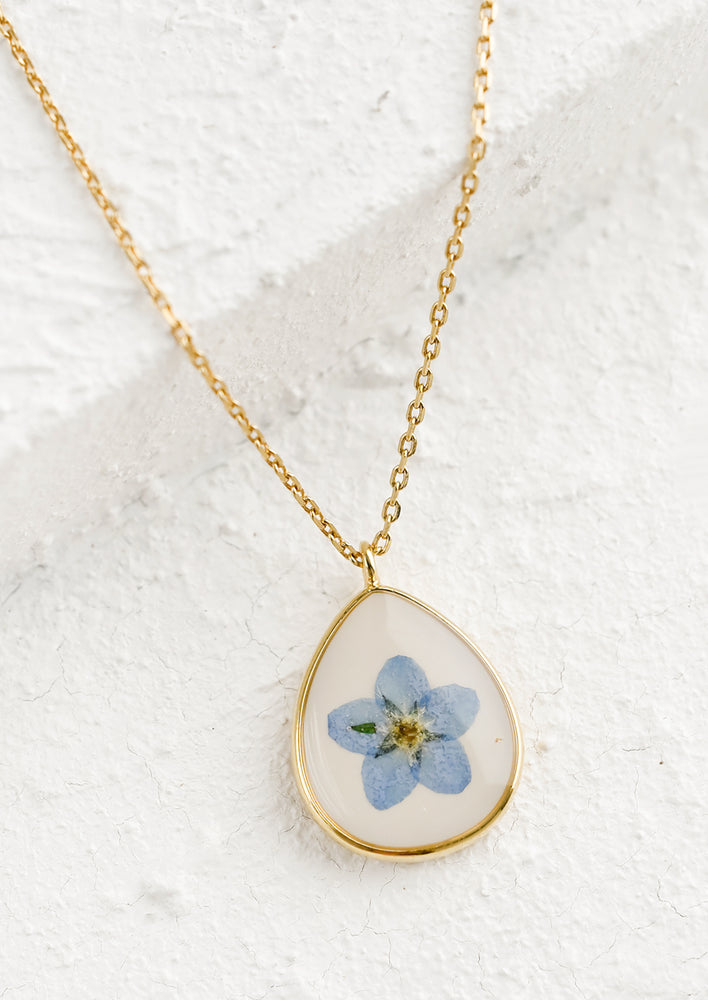 A gold necklace with resin floral charm pendant.