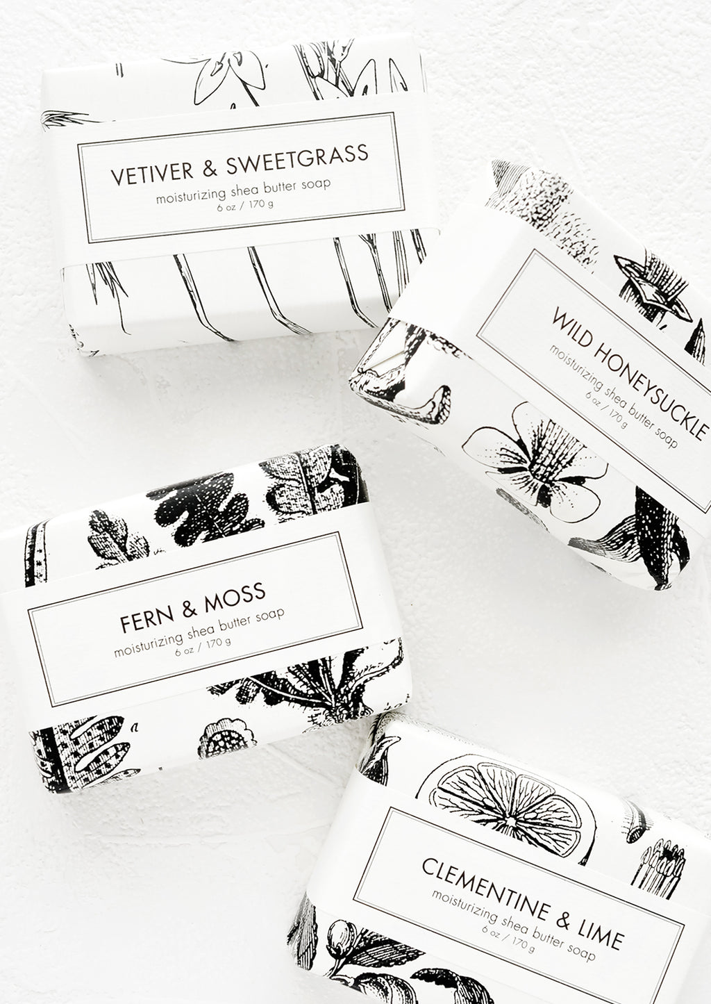 1: Four bars of soap in black & white botanical graphic packaging.