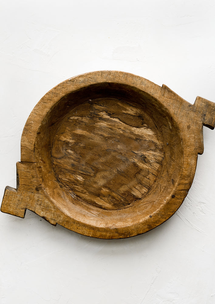 2: A round antique wooden tray with decorative side handles.