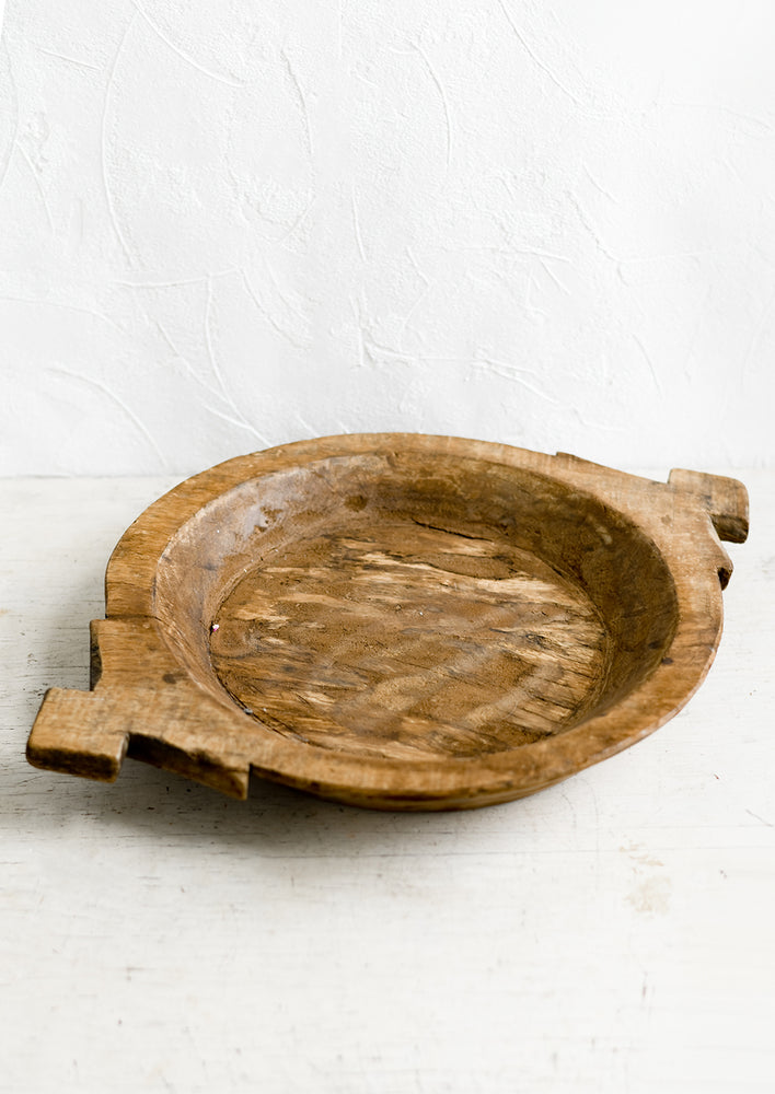 1: A round antique wooden tray with decorative side handles.