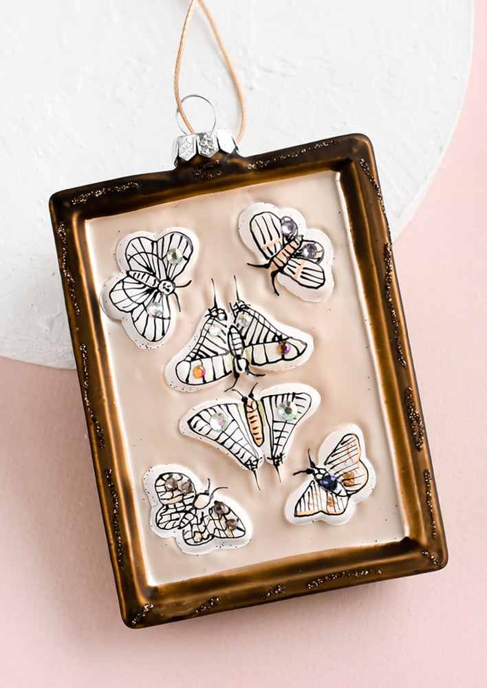 A decorative glass ornament in shape of picture frame showcasing butterflies.