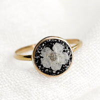 Size 6 / Black: A gold round bezel ring showing white flower on black background.