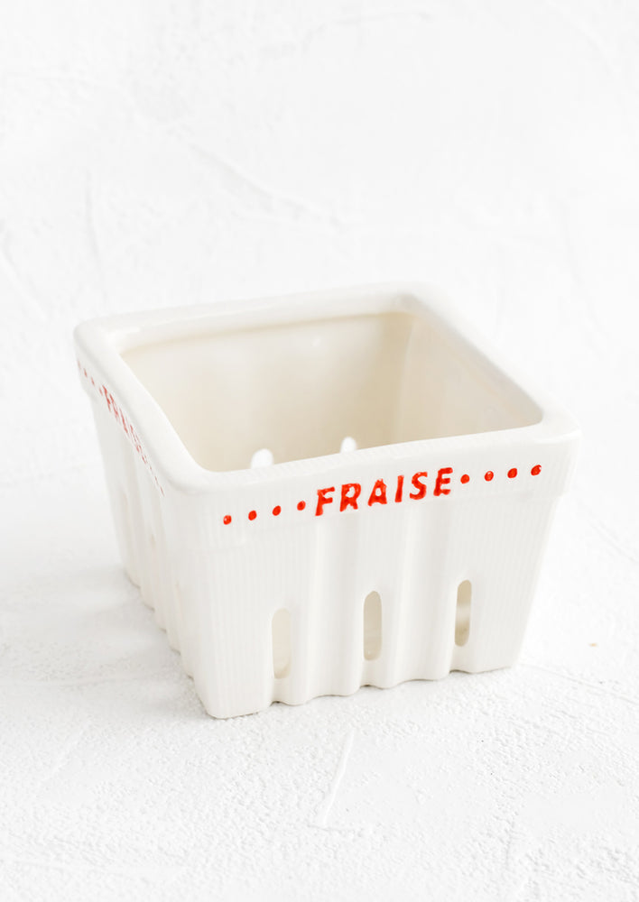 A white ceramic basket designed to look like a berry basket with "Fraise" printed in red lettering.