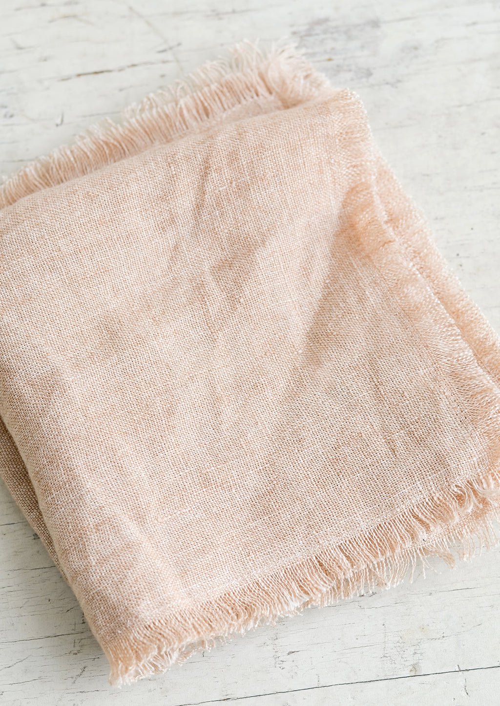 Dusty Rose: A folded dusty pink linen napkin with frayed edges.