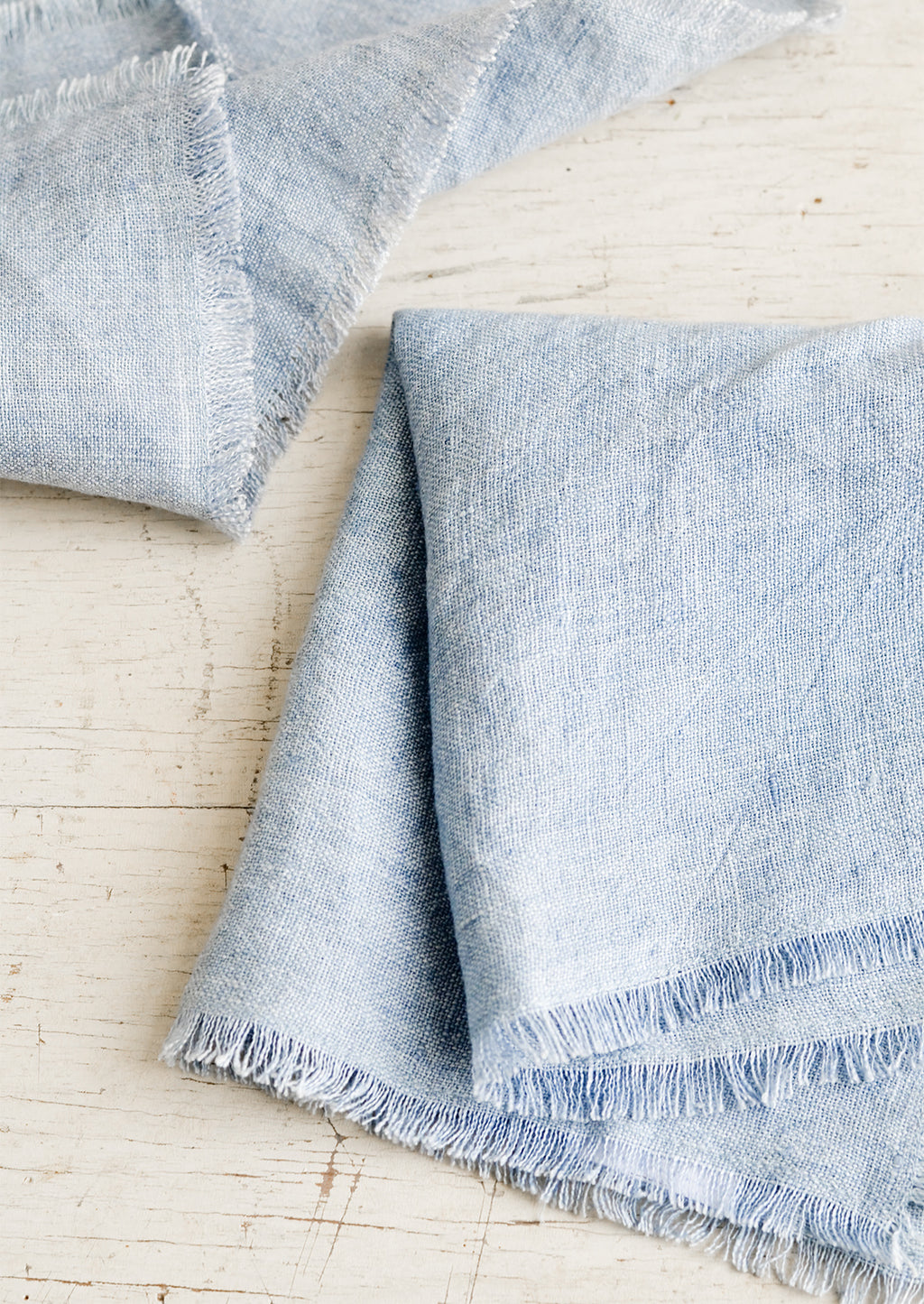 Chambray Blue: Folded blue linen napkins with frayed edges.