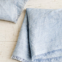 Chambray Blue: Folded blue linen napkins with frayed edges.