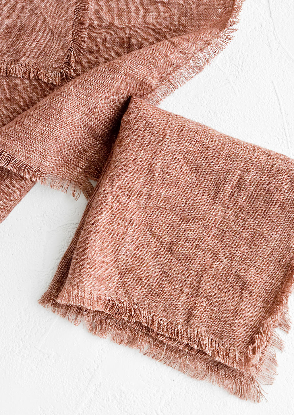 Currant: Folded currant colored linen napkins with frayed edges.