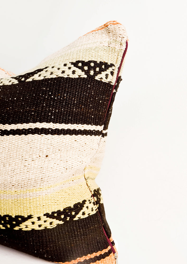 Square throw pillow in wool fabric with tan and black stripes, accents of orange and yellow.