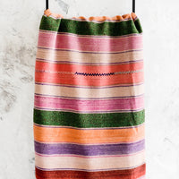 2: Colorful, striped woven textile intended for use as a rug or blanket, hung on a display ladder.