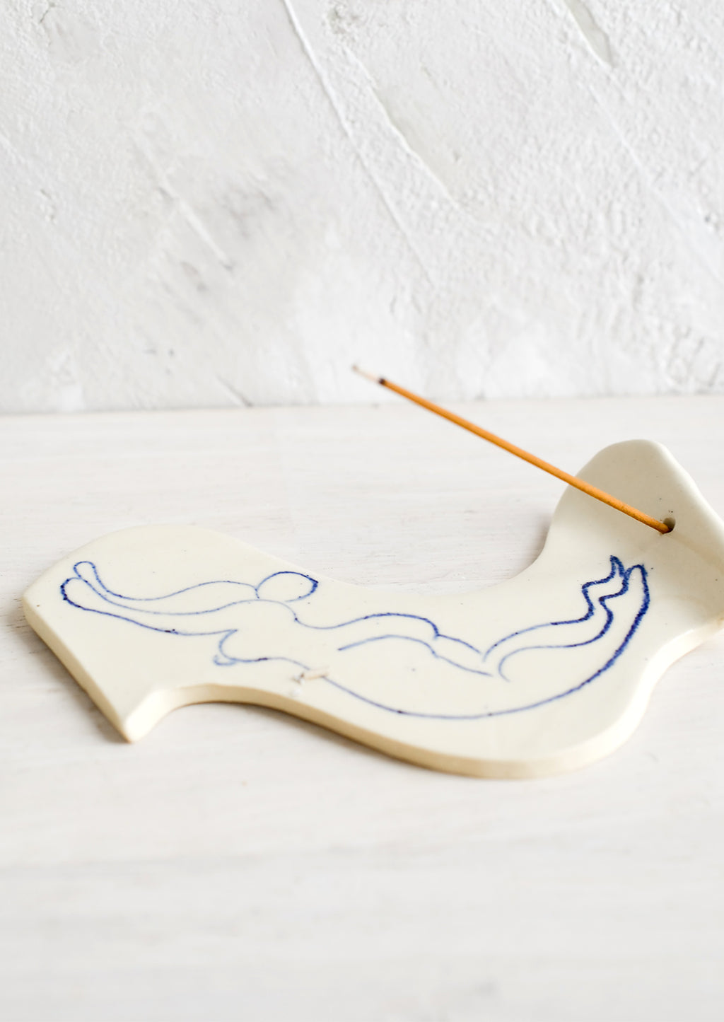 2: A ceramic incense holder with line drawn naked woman diving.