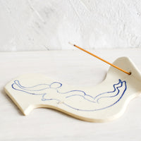 2: A ceramic incense holder with line drawn naked woman diving.