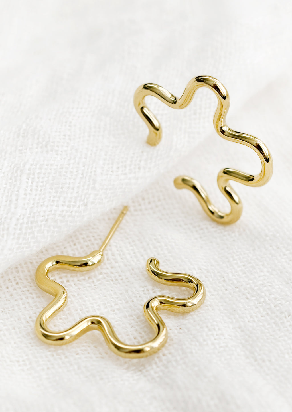 2: A pair of gold flower outline earrings.