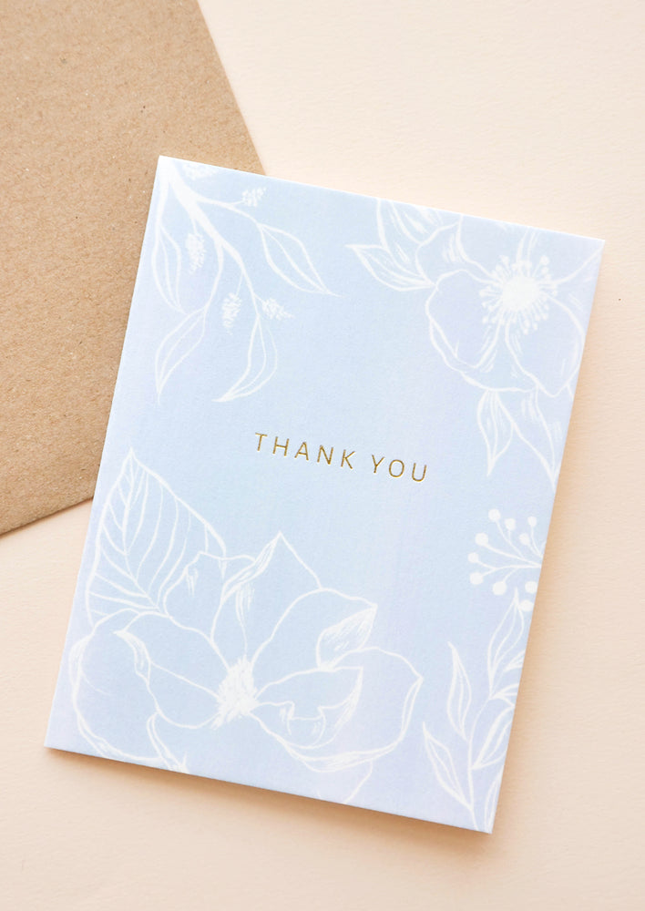 1: Pale blue notecard with white floral decoration and the text "thank you", with brown envelope.
