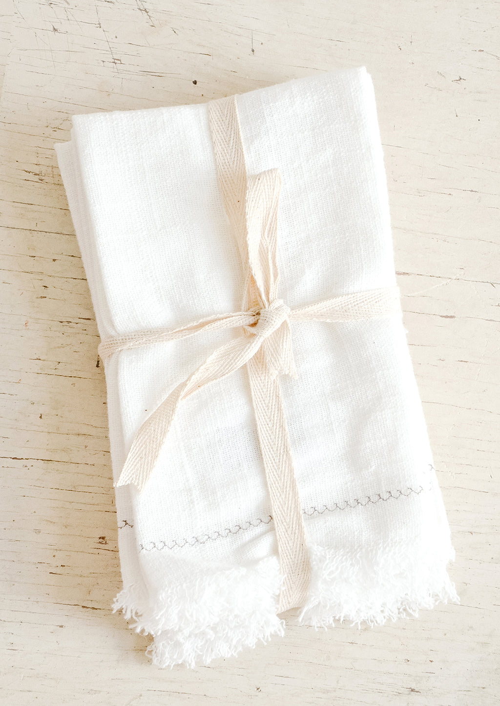 1: White cotton dinner napkins folded and bound with twine