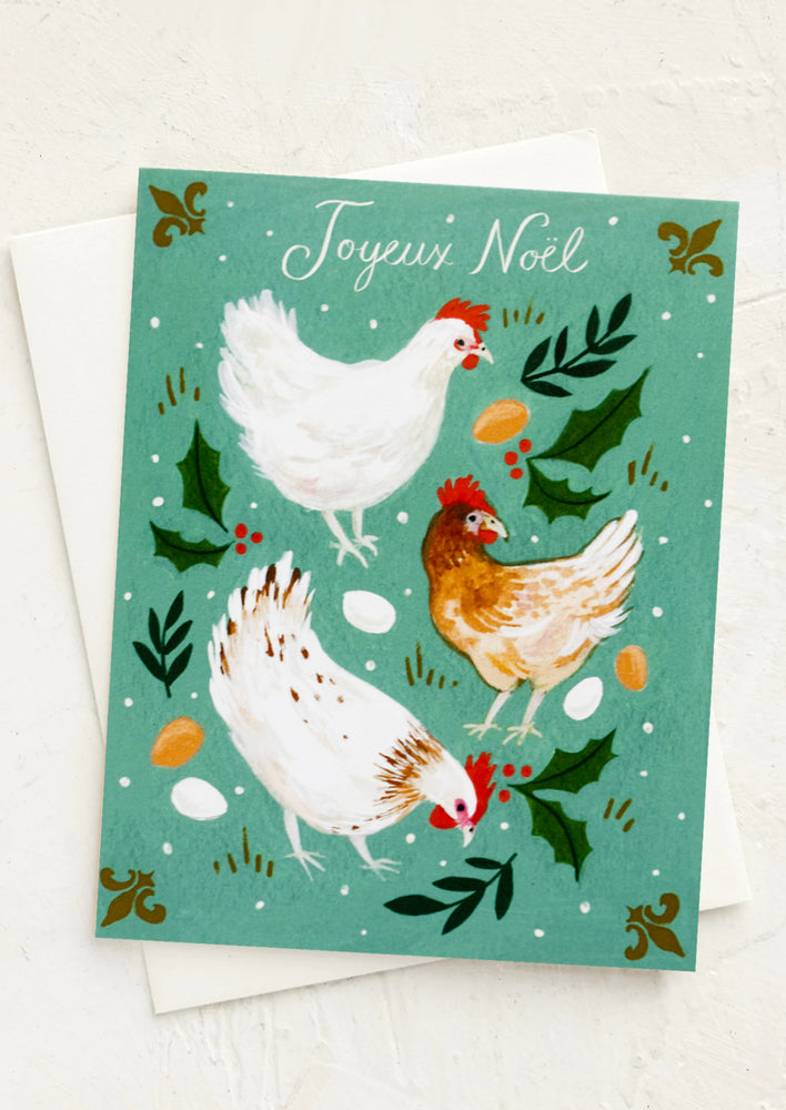 A card with holly illustration and three hens, text at top reads "Joyeux Noel".