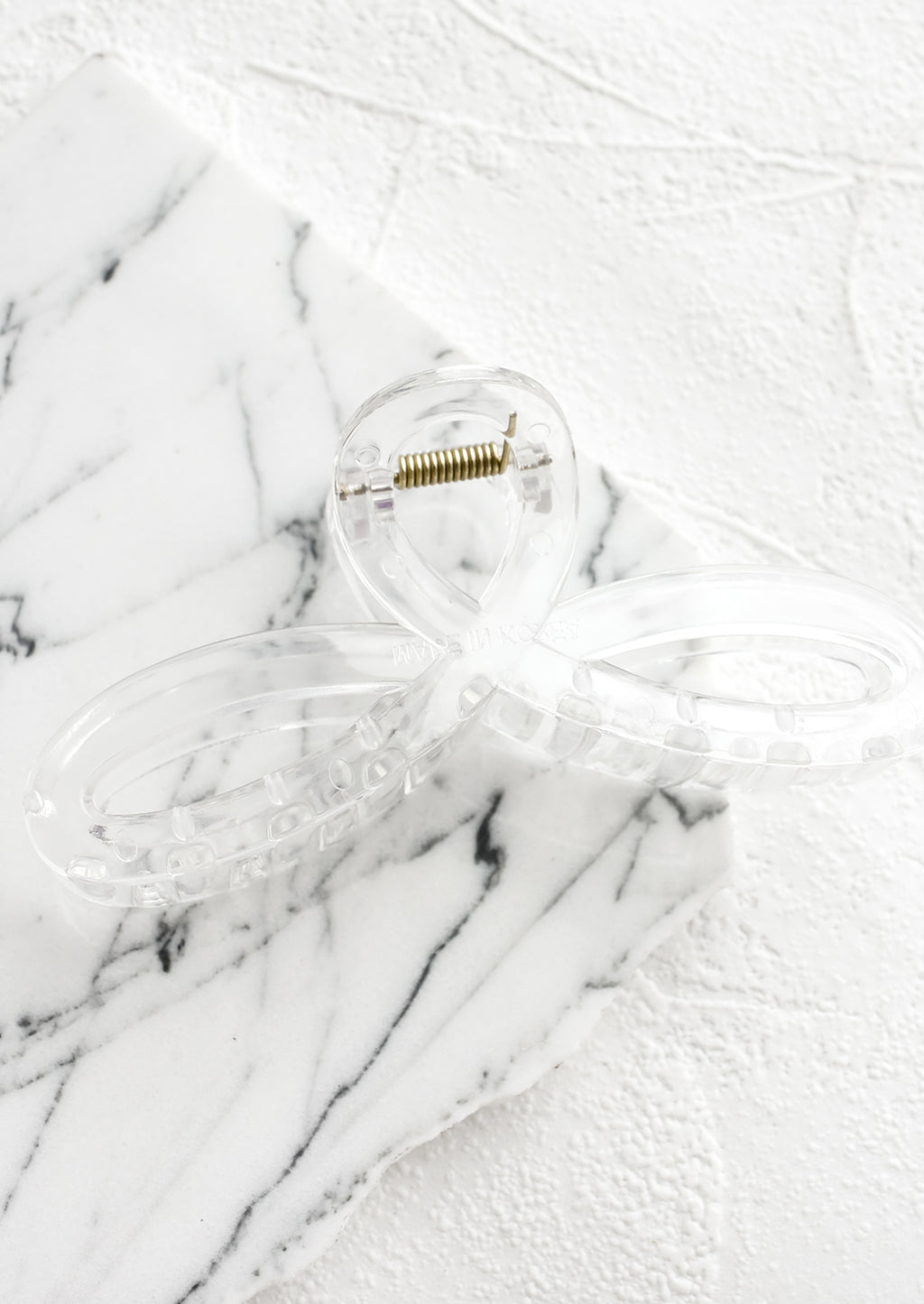 Clear: A curvy hair clip with knotted loop design in clear.