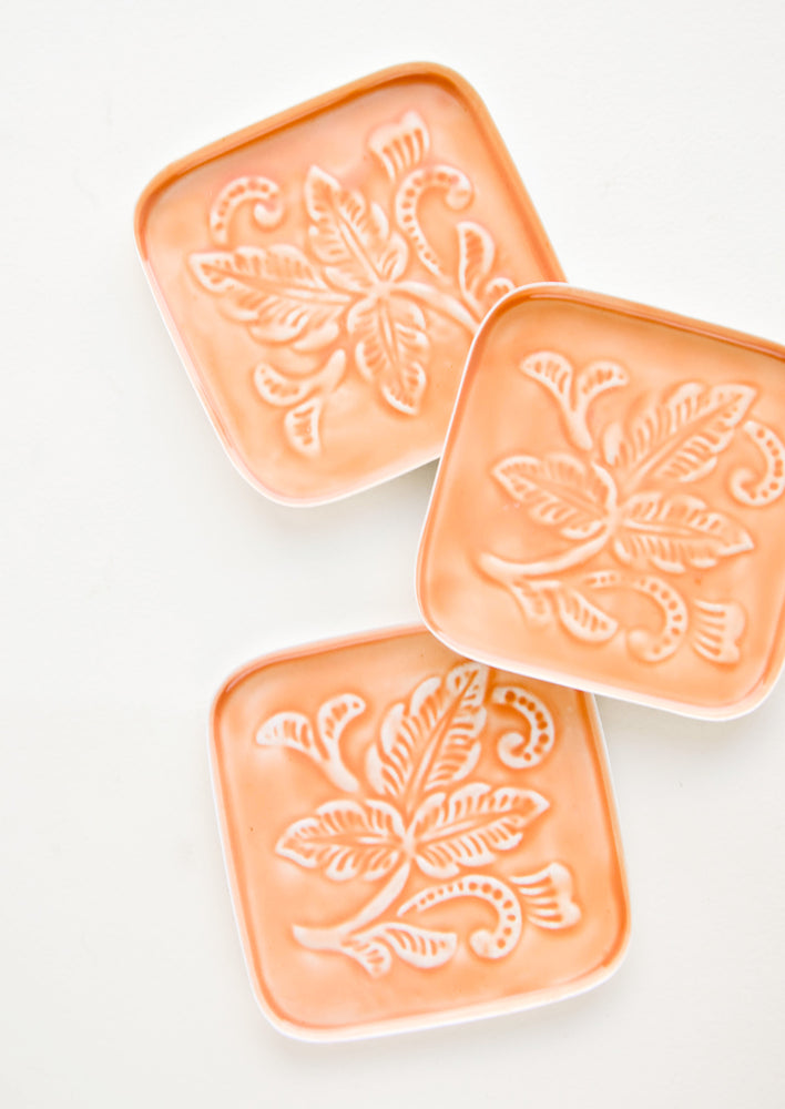 Square coasters in peach enamel with raised floral motif
