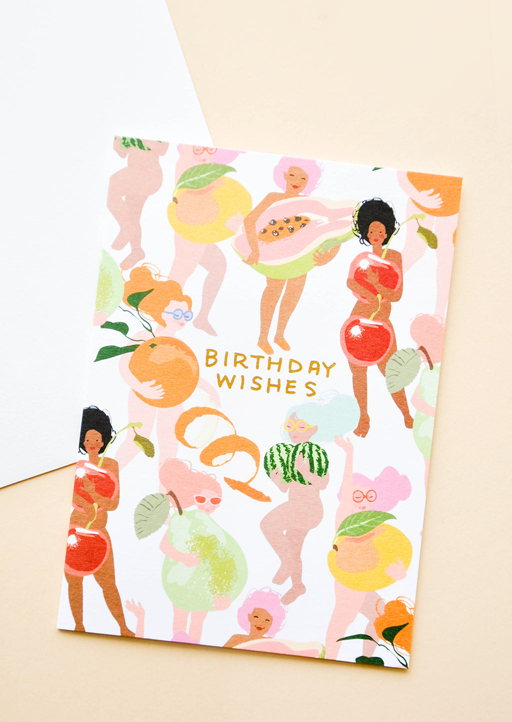 1: Greeting card with illustrated people, covering themselves with fruit. "Birthday Wishes" written in orange text. Shown with white envelope. 