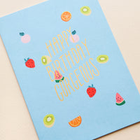 2: Greeting card with blue background and small fruits printed allover, golden lettering reads "Happy Birthday Gorgeous"