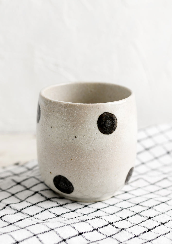 Natural: A white ceramic cup with black polka dots.