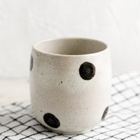 Natural: A white ceramic cup with black polka dots.