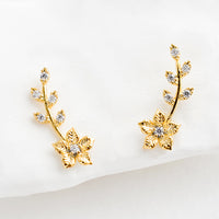 1: A pair of gold climber stud earrings with floral design decorated with crystals.