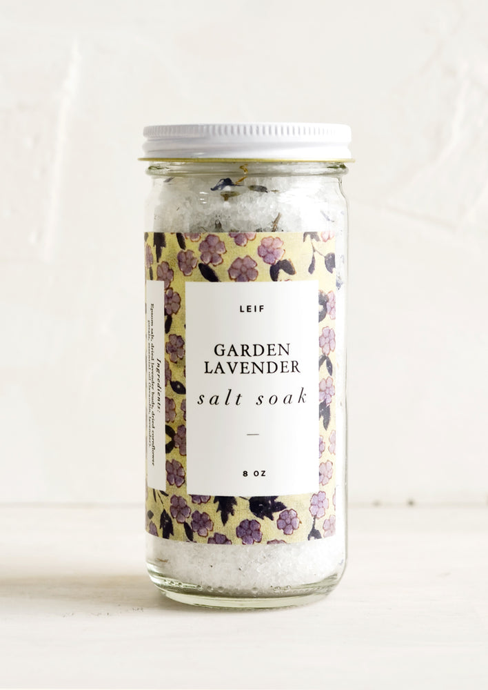 A straight sided glass jar containing Garden Lavender salt soak.