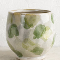 1: A footed planter with green paint stroke pattern.