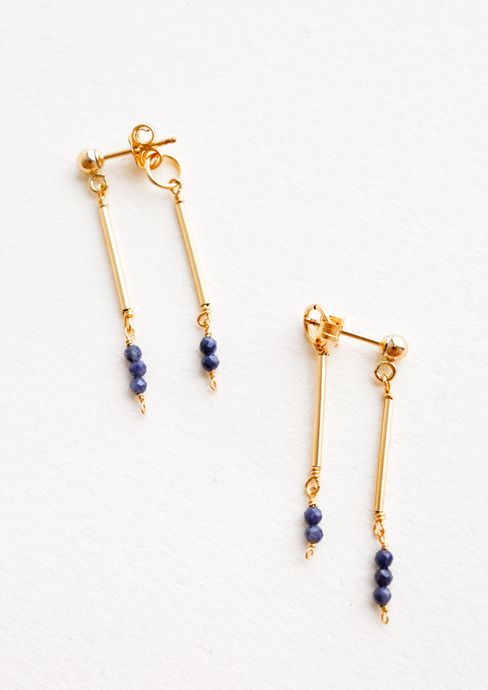 Sapphire: Two part dangling earrings featuring gold post and blue beads hanging from each of the post and the earring back.