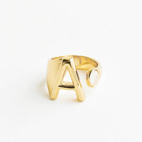 A: Yellow gold ring with letter A and oval glass crystal, and wide adjustable band.