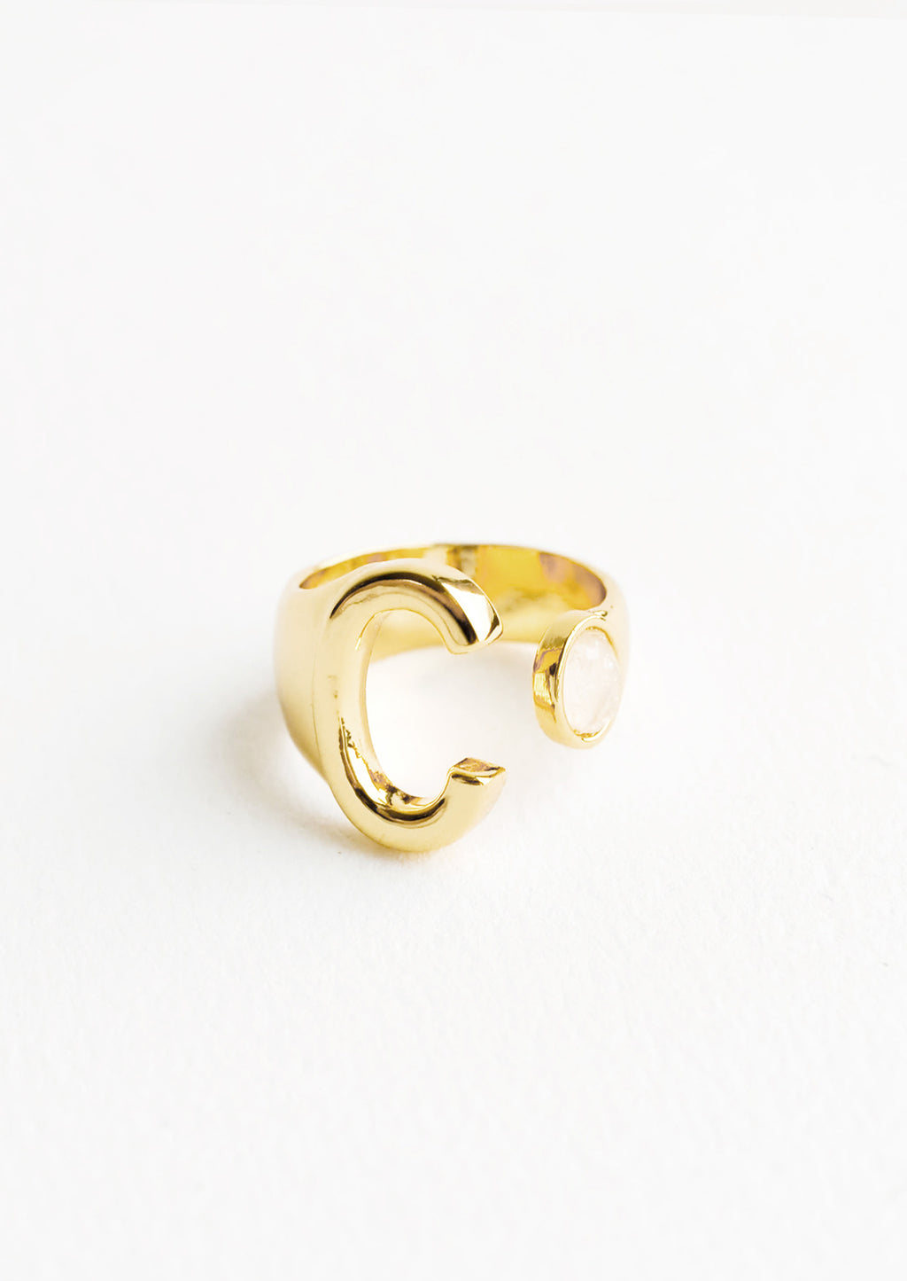 C: Yellow gold ring with letter C and oval glass crystal, and wide adjustable band.