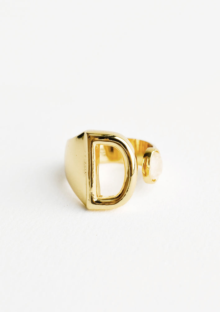 D: Yellow gold ring with letter D and oval glass crystal, and wide adjustable band.