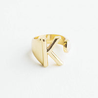 K: Yellow gold ring with letter K and oval glass crystal, and wide adjustable band.