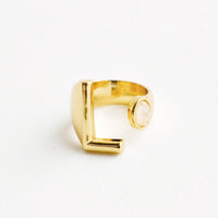 11: Yellow gold ring with letter L and oval glass crystal, and wide adjustable band.