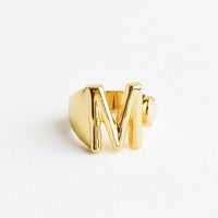 M: Yellow gold ring with letter M and oval glass crystal, and wide adjustable band.