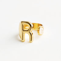 R: Yellow gold ring with letter R and oval glass crystal, and wide adjustable band.