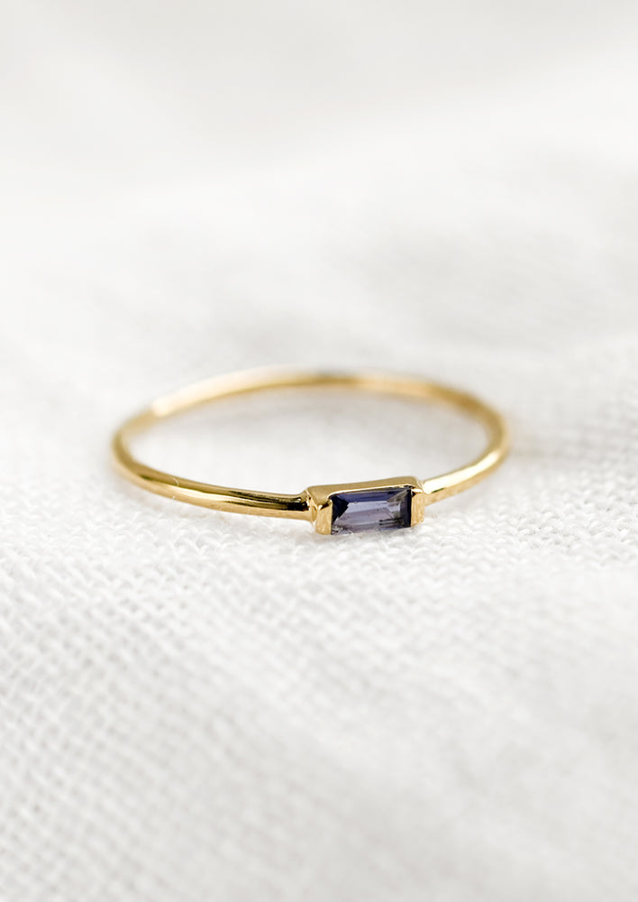 A gold ring with slim baguette stone in iolite.