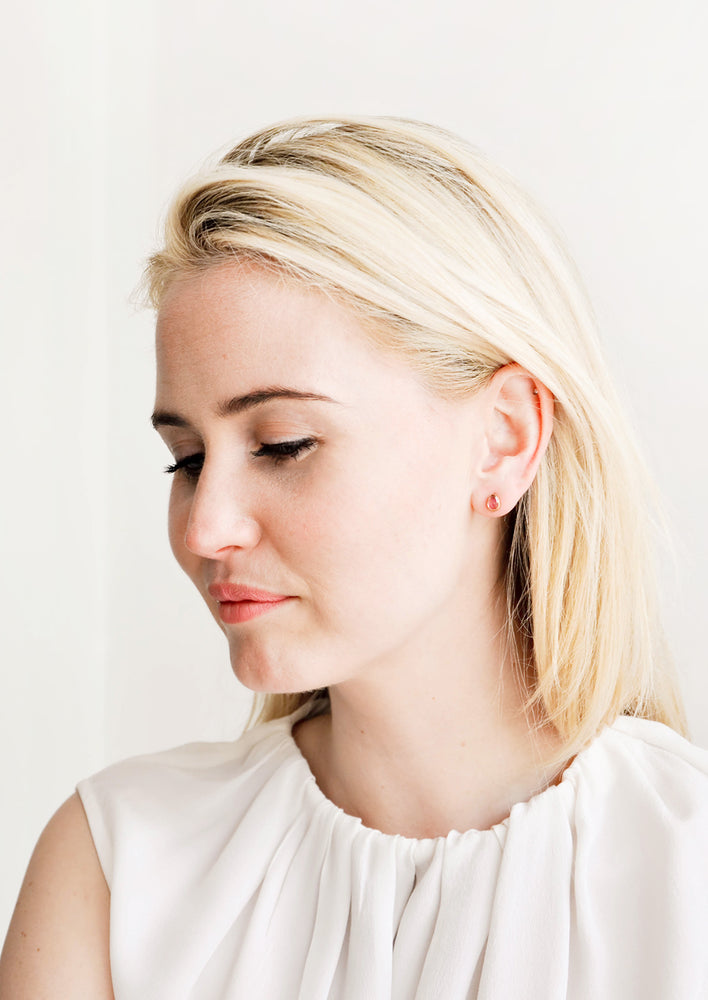 3: Model shot of woman wearing stud earrings and white top.