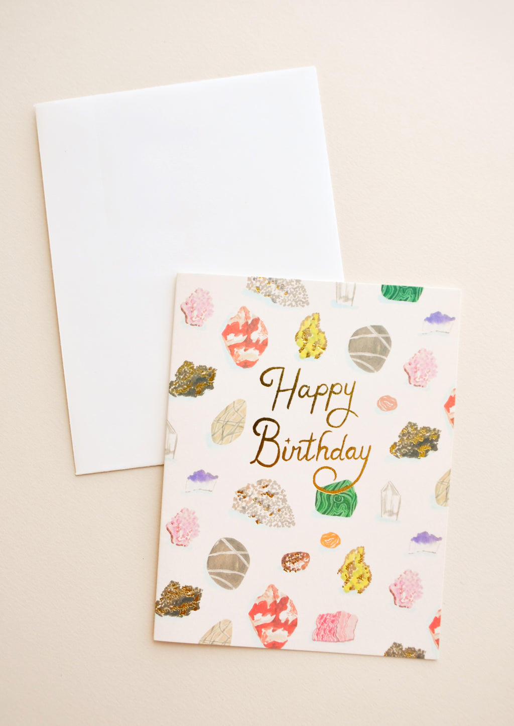 1: Notecard with colorful drawings of gems and minerals and the text "Happy Birthday" in gold foil, with white envelope.