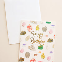 1: Notecard with colorful drawings of gems and minerals and the text "Happy Birthday" in gold foil, with white envelope.