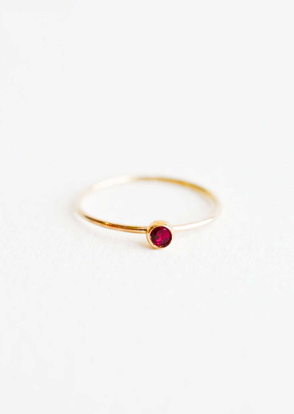 Garnet / Size 5: Yellow gold ring with slim band and small red garnet stone.