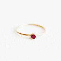 Garnet / Size 5: Yellow gold ring with slim band and small red garnet stone.