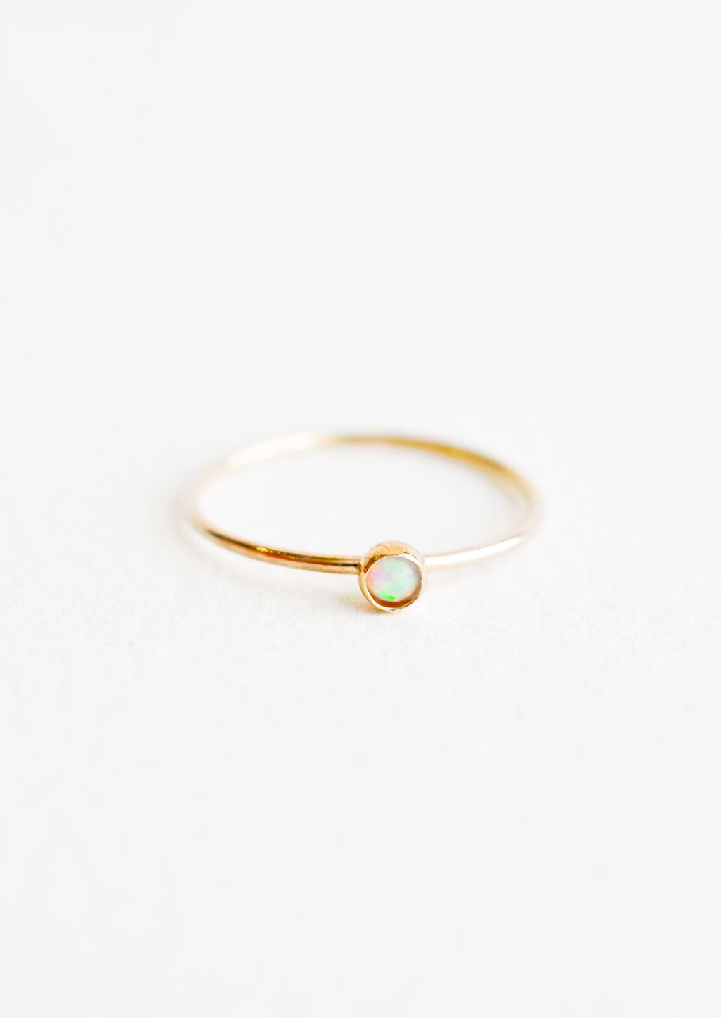 Opal / Size 5: Yellow gold ring with slim band and small white opal stone.
